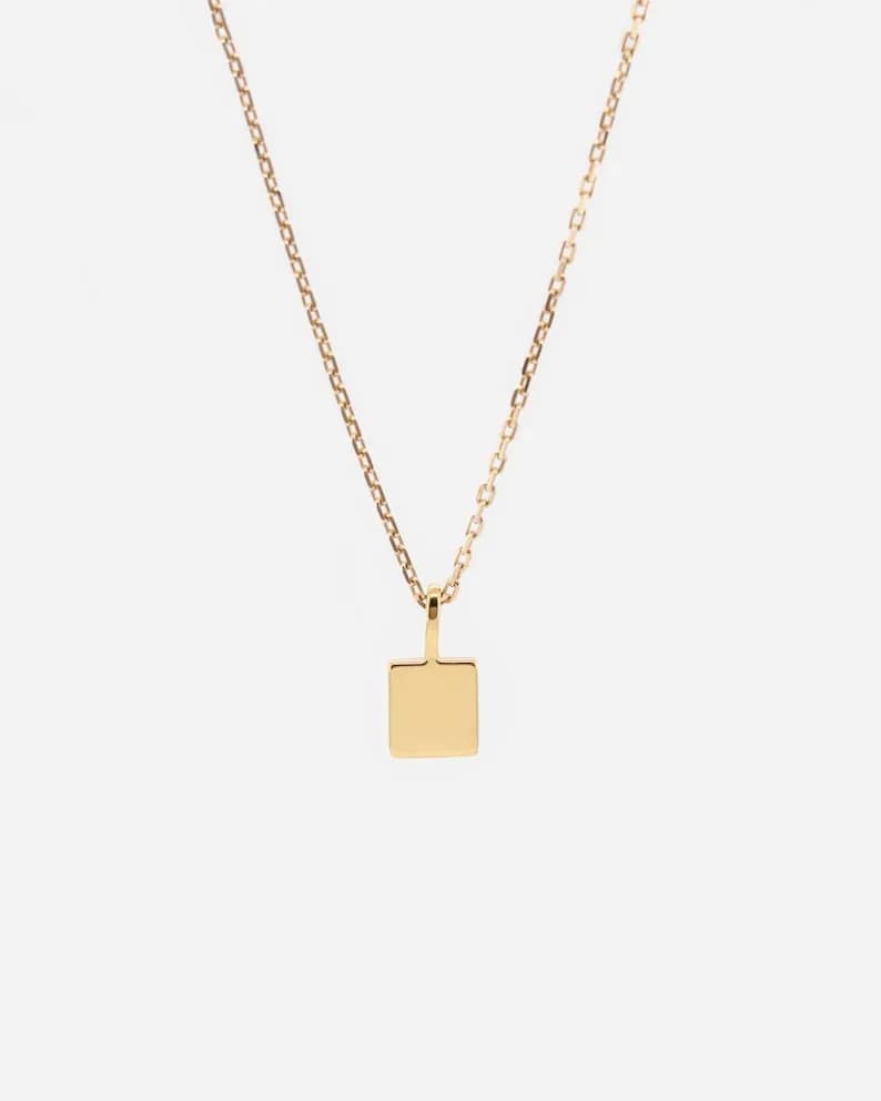Gold chain necklace with a small square pendant.