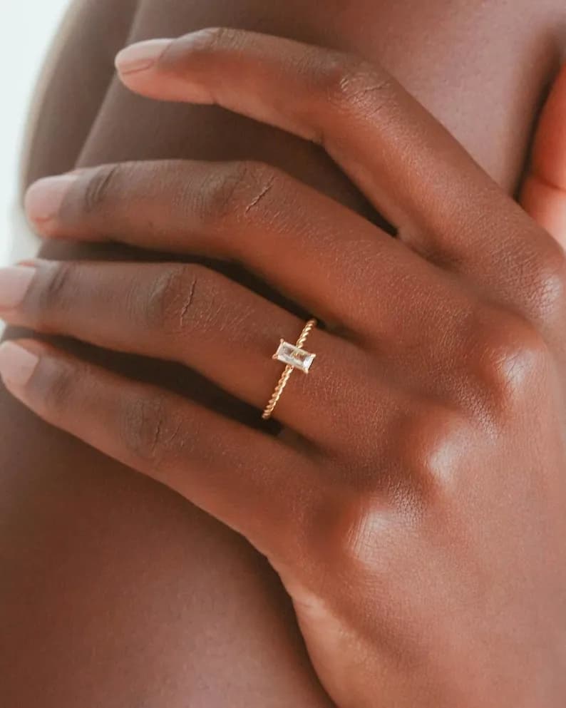 Gold ring with a clear rectangular gemstone set in a twisted band.