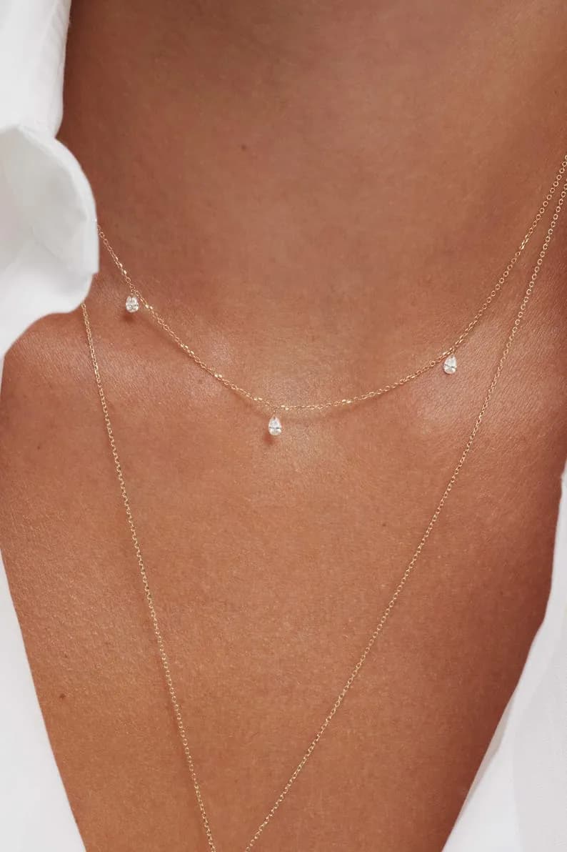 Delicate gold necklace featuring three small, sparkling diamond pendants, layered with a second gold chain.